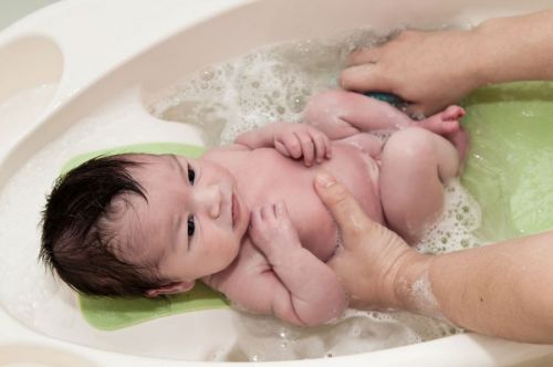 Младенец принимает хвойную ванну